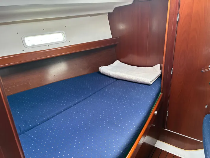 Danae Yacht Photos Pics Cozy cabin interior of 2003 Beneteau Oceanis Clipper 393 with blue bedding and wooden finish.