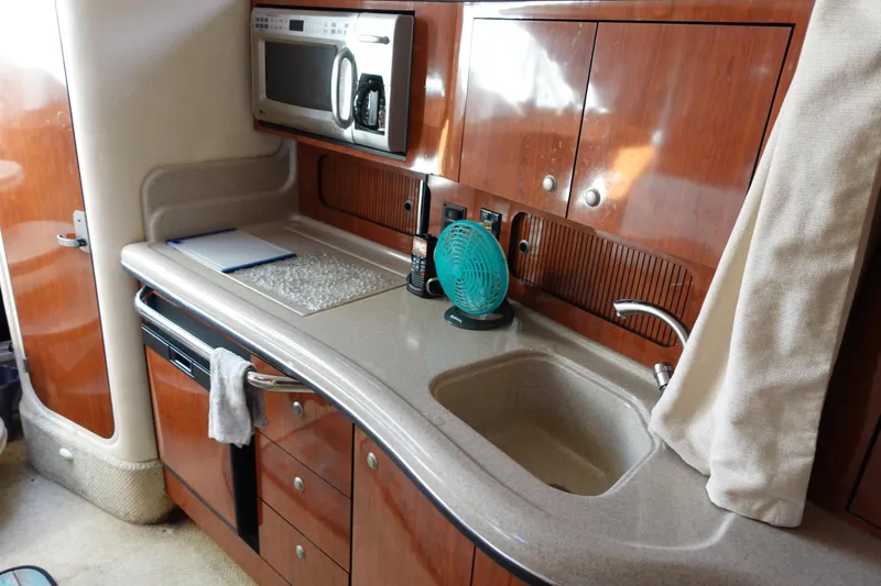  Yacht Photos Pics 2007 Sea Ray 320 Sundancer kitchen with microwave, sink, and wooden cabinetry.