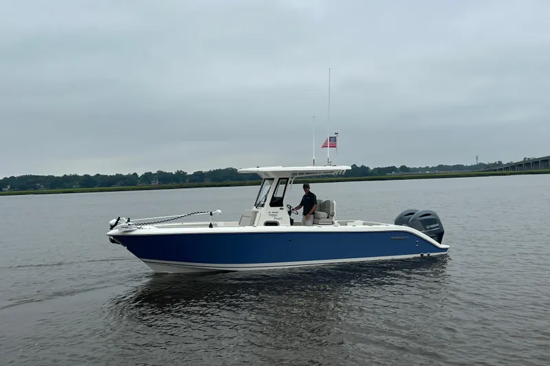 Happy Hours Yacht Photos Pics 2023 Pursuit S 268 Sport boat cruising on a calm lake under cloudy skies.