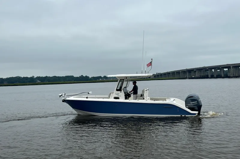 Happy Hours Yacht Photos Pics 2023 Pursuit S 268 Sport boat cruising on a calm river near a bridge.