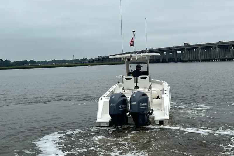 Happy Hours Yacht Photos Pics 2023 Pursuit S 268 Sport boat cruising on a river near a bridge.