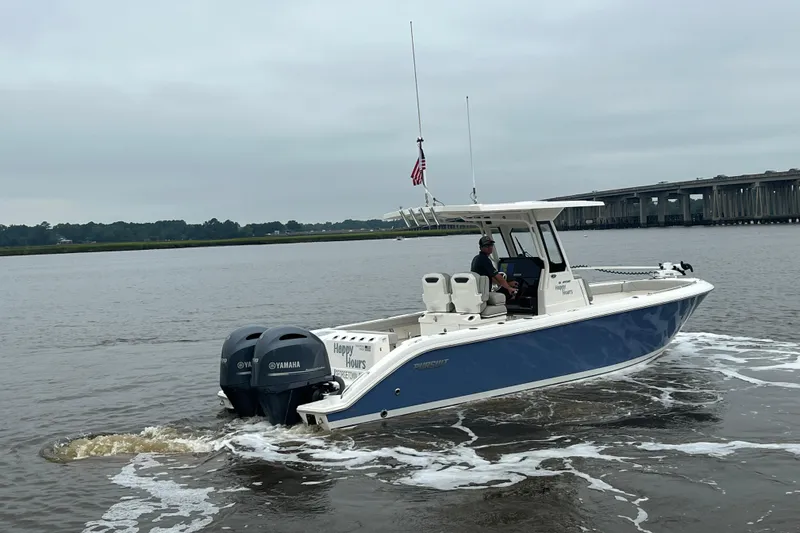 Happy Hours Yacht Photos Pics 2023 Pursuit S 268 Sport boat cruising on a river near a bridge.