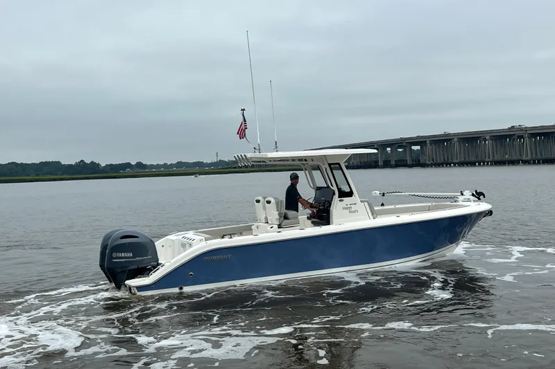 Happy Hours Yacht Photos Pics 2023 Pursuit S 268 Sport boat cruising on a calm river near a bridge.