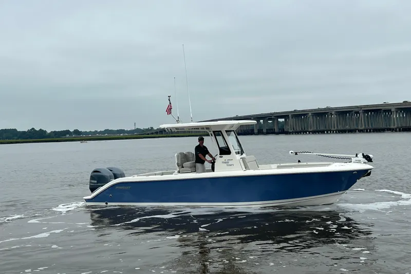 Happy Hours Yacht Photos Pics 2023 Pursuit S 268 Sport boat on calm water near a bridge.