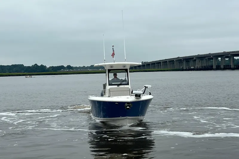 Happy Hours Yacht Photos Pics 2023 Pursuit S 268 Sport boat cruising on a calm river near a bridge.