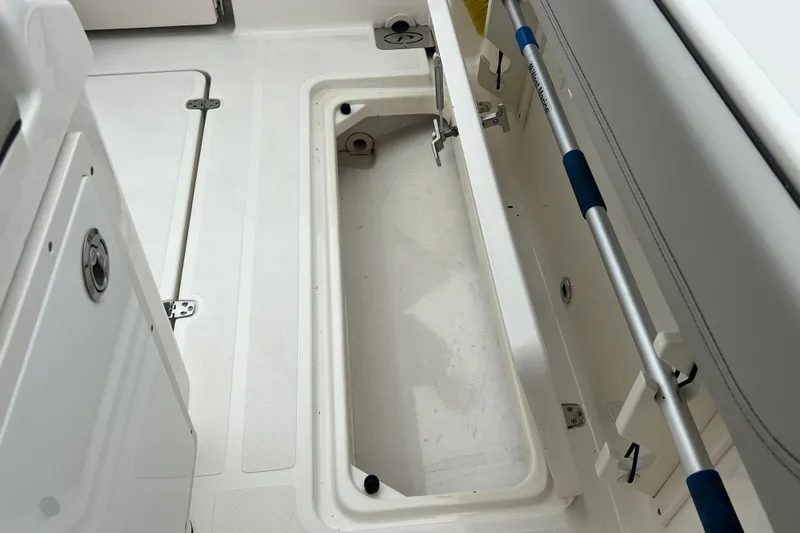 Happy Hours Yacht Photos Pics 2023 Pursuit S 268 Sport boat storage compartment with open hatch and cleaning brush.