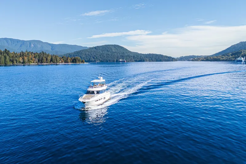 Luna Maris Yacht Photos Pics 2016 Prestige 550 Flybridge yacht cruising on a serene lake with scenic mountain backdrop.