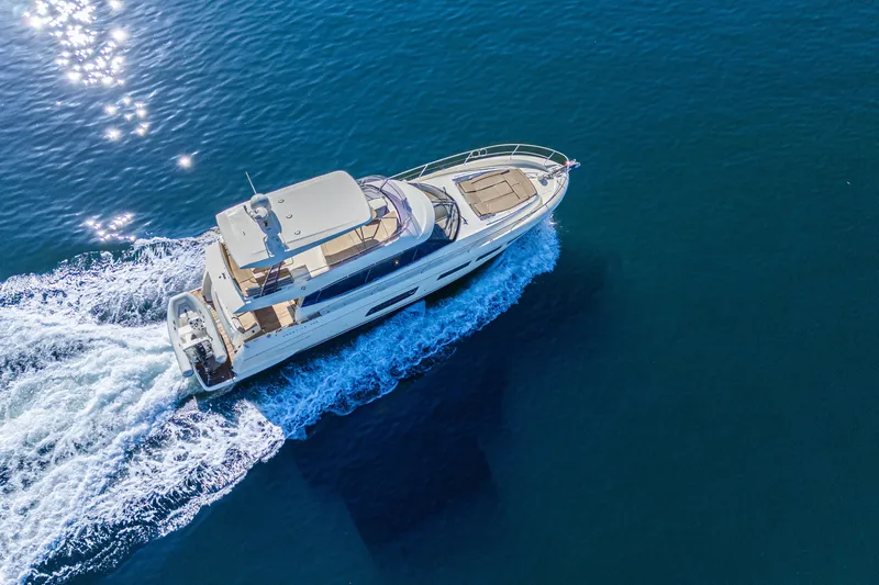Luna Maris Yacht Photos Pics Aerial view of 2016 Prestige 550 Flybridge yacht cruising on blue ocean waters.