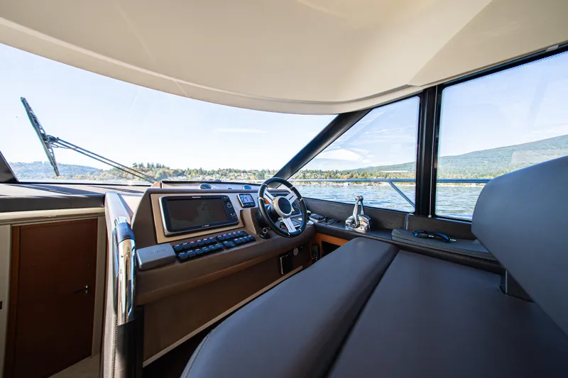 Luna Maris Yacht Photos Pics Interior view of 2016 Prestige 550 Flybridge yacht cockpit with scenic water backdrop.