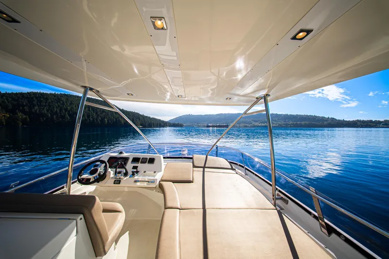 Luna Maris Yacht Photos Pics Luxurious 2016 Prestige 550 Flybridge yacht on serene lake with scenic forest backdrop.