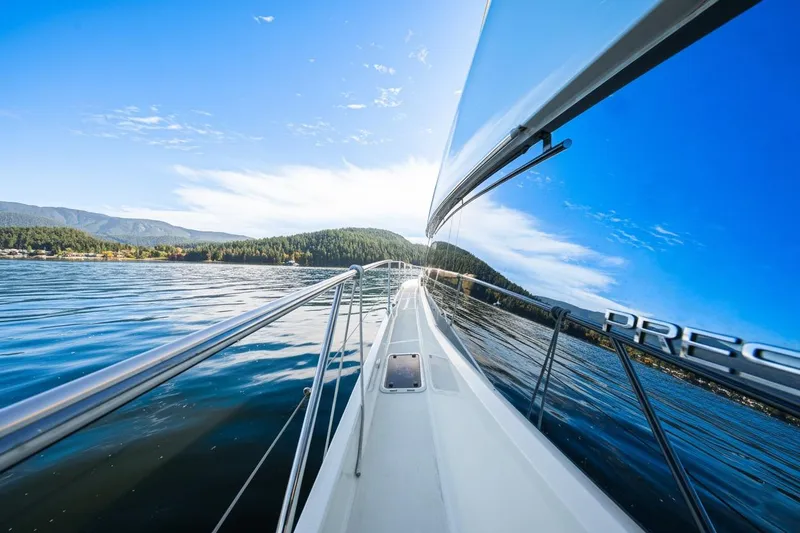 Luna Maris Yacht Photos Pics Prestige 550 Flybridge yacht cruising on serene waters, reflecting clear blue sky, 2016 model.