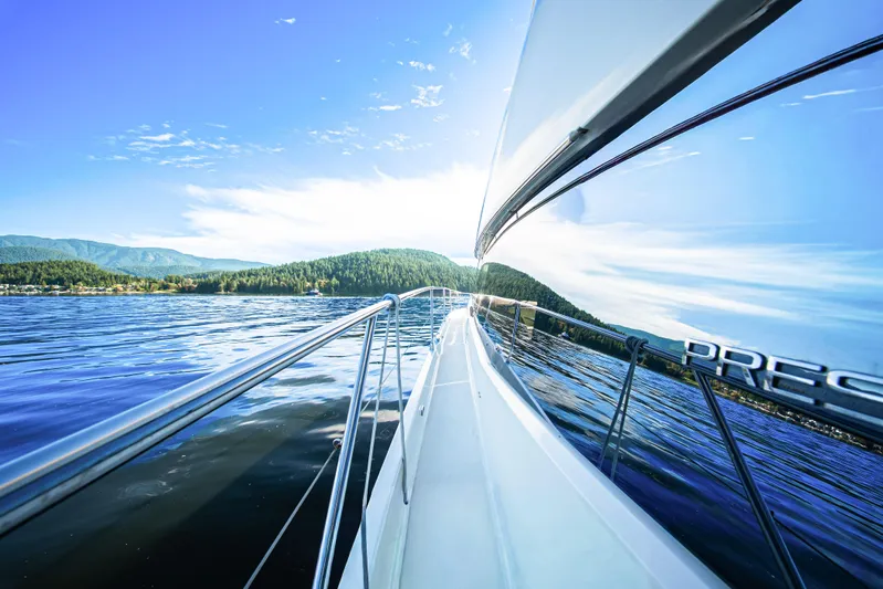 Luna Maris Yacht Photos Pics Luxury yacht Prestige 550 cruising on a serene lake, reflecting clear blue skies.