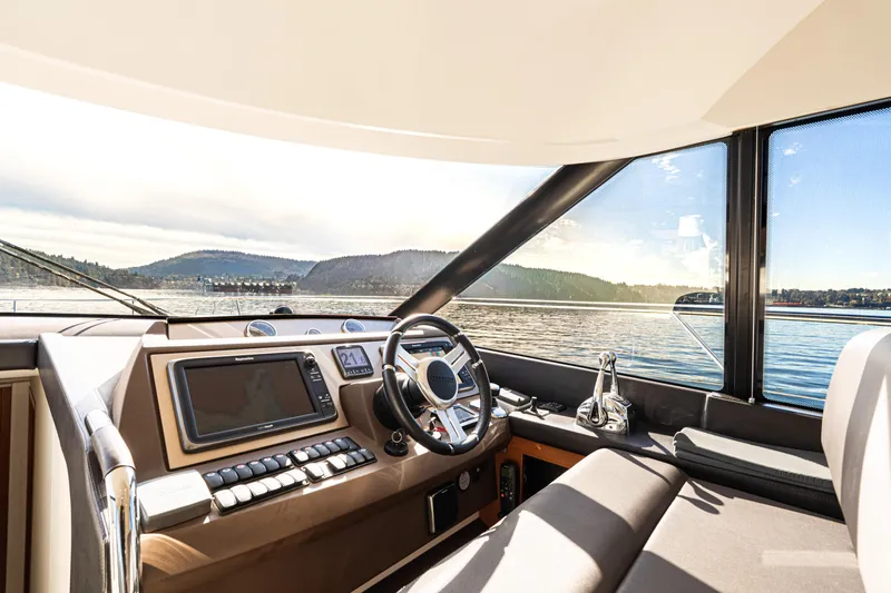 Luna Maris Yacht Photos Pics Interior view of 2016 Prestige 550 yacht cockpit with scenic water and mountain backdrop.