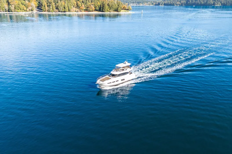 Luna Maris Yacht Photos Pics Prestige 550 yacht cruising on serene blue waters, surrounded by lush green shoreline.