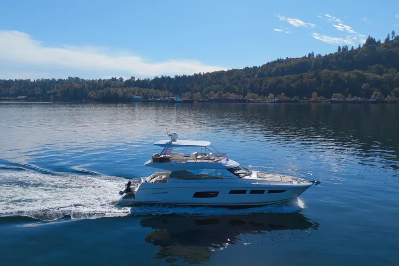Luna Maris Yacht Photos Pics Luxury 2016 Prestige 550 yacht cruising on a serene lake with forested hills.