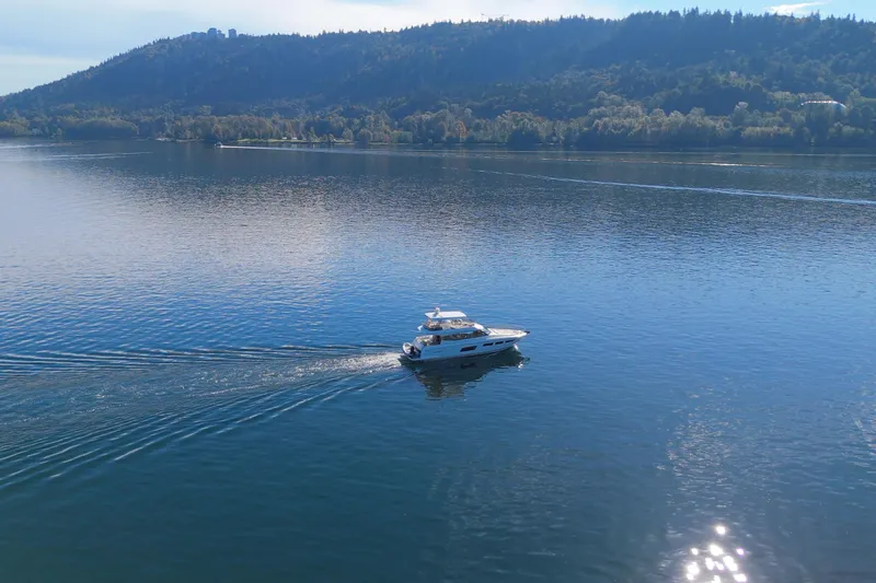 Luna Maris Yacht Photos Pics 2016 Prestige 550 yacht cruising on a serene lake with forested hills in the background.