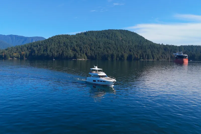 Luna Maris Yacht Photos Pics Prestige 550 yacht cruising on a serene lake with forested hills in the background.