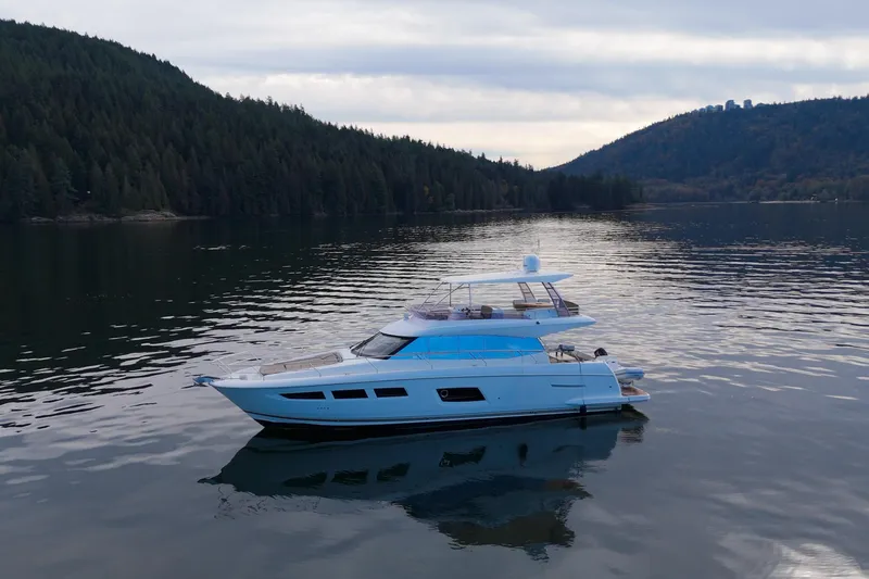 Luna Maris Yacht Photos Pics Luxurious 2016 Prestige 550 yacht cruising on serene lake with forested hills in the background.