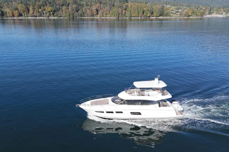 Luna Maris Yacht Photos Pics 2016 Prestige 550 yacht cruising on a serene lake with forested shoreline.