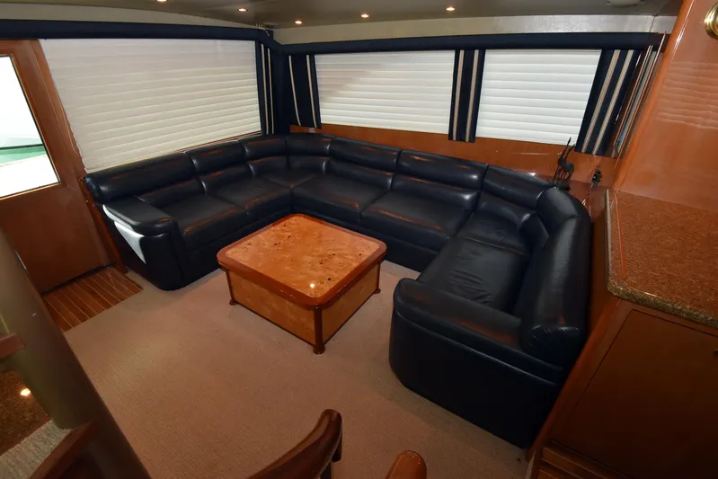 Bella Betty Yacht Photos Pics Luxurious interior of 2003 Viking 65 Enclosed Bridge yacht with leather seating and wooden table.