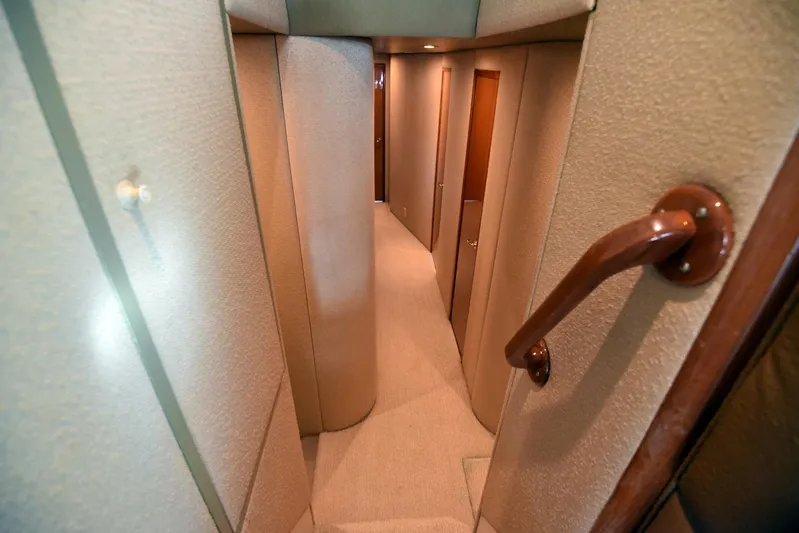 Bella Betty Yacht Photos Pics Interior hallway of 2003 Viking 65 Enclosed Bridge yacht, featuring carpeted floors and wooden accents.