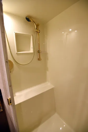 Bella Betty Yacht Photos Pics Shower area in 2003 Viking 65 Enclosed Bridge yacht, featuring a built-in seat and gold fixtures.