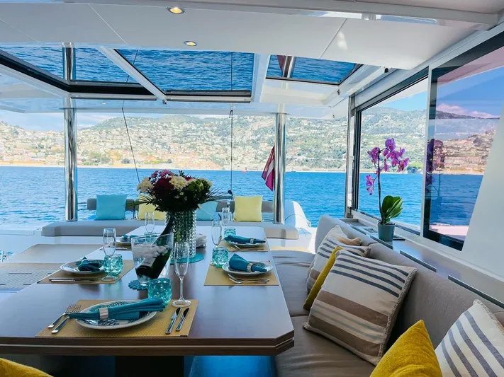 Signature Bali 5.4. (6+ 2 Cabins) Yacht Photos Pics Luxurious Bali 5.4 yacht interior with elegant dining setup, ocean view, and vibrant decor, 2022 model.