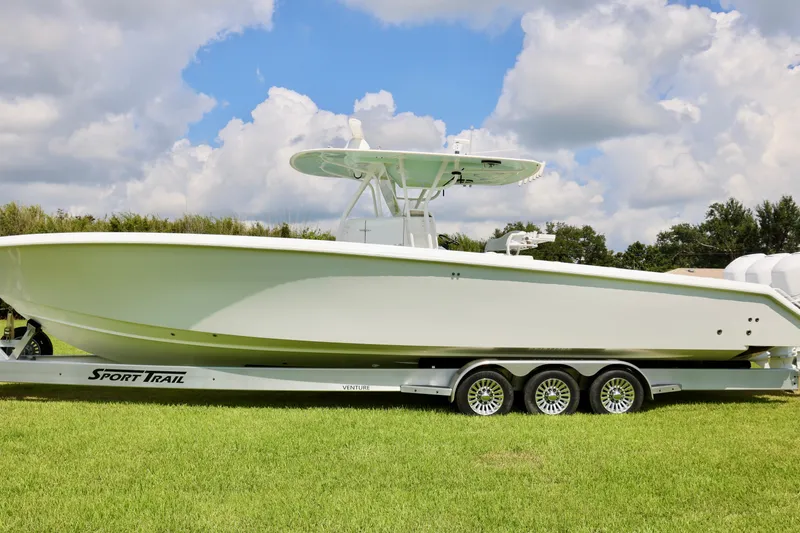  Yacht Photos Pics 2005 Venture 39 Open boat on Sport Trail trailer, parked on grass under a cloudy sky.