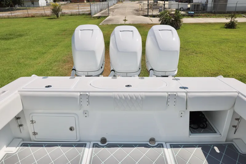  Yacht Photos Pics 2005 Venture 39 Open boat with triple outboard engines on grassy area.