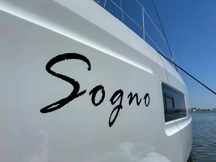 Sogno Yacht Photos Pics 2024 Lagoon 46 catamaran with "Sogno" name, sleek design, and clear blue sky background.
