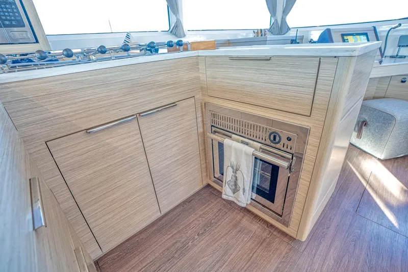 Sogno Yacht Photos Pics Modern kitchen interior of 2024 Lagoon 46 yacht with wood finish and built-in oven.