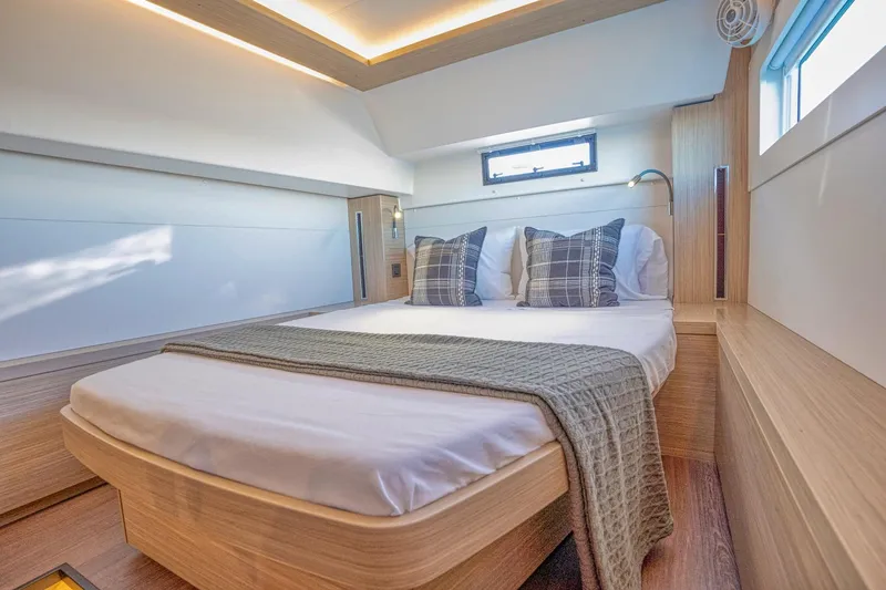Sogno Yacht Photos Pics Luxurious cabin interior of 2024 Lagoon 46 yacht with modern bedding and natural lighting.