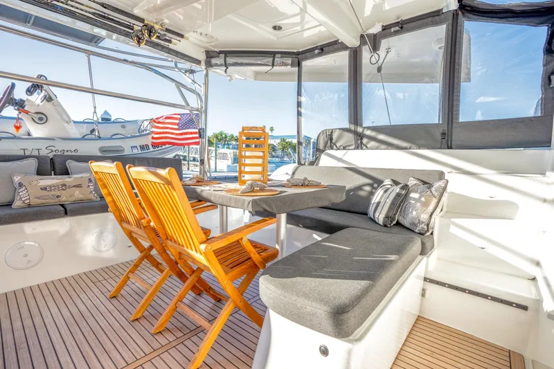 Sogno Yacht Photos Pics 2024 Lagoon 46 yacht interior with wooden chairs, table, and cushioned seating.