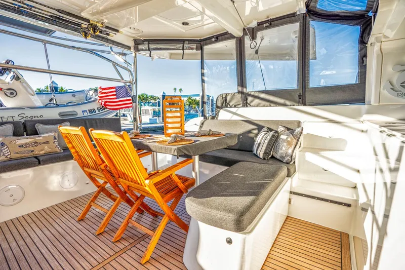 Sogno Yacht Photos Pics 2024 Lagoon 46 yacht interior with dining area, wooden chairs, and plush seating.