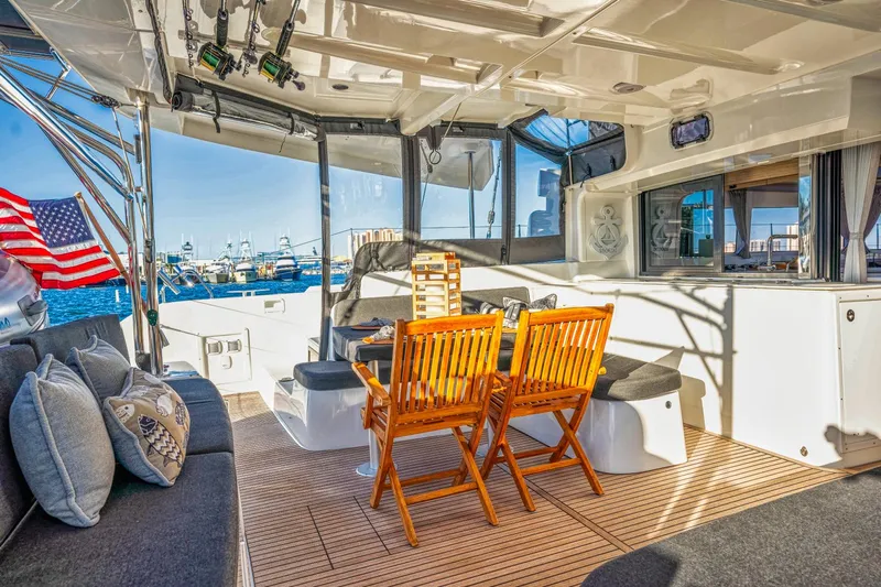 Sogno Yacht Photos Pics 2024 Lagoon 46 yacht interior with wooden chairs, cozy seating, and an American flag.