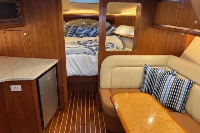 The Riddler Yacht Photos Pics 2009 Tiara Yachts 3600 Open interior with cozy cabin, striped pillows, and wooden finishes.