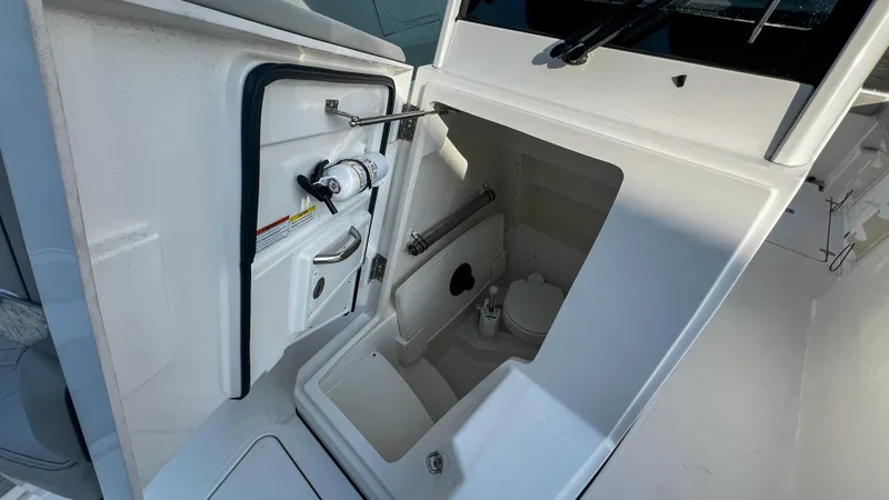  Yacht Photos Pics 2022 Pursuit S 268 boat interior with compact marine toilet and storage compartment.