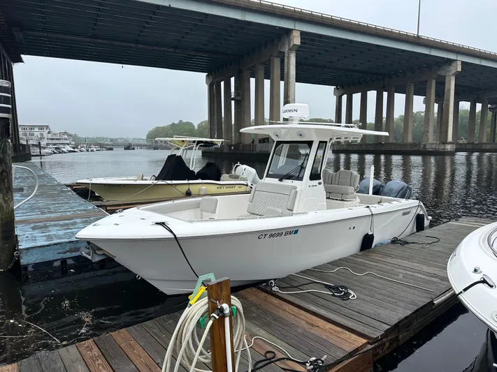  Yacht Photos Pics 2022 Pursuit S 268 boat docked under a bridge on a calm river.