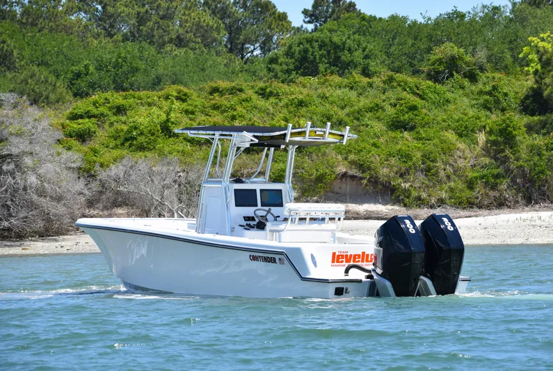  Yacht Photos Pics 2024 Contender 28 Tournament boat cruising near a lush, green shoreline.