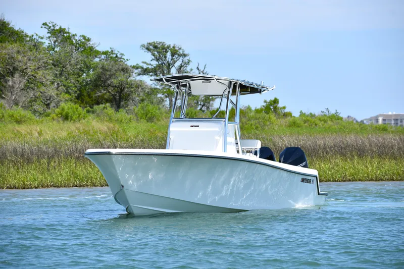  Yacht Photos Pics 2024 Contender 28 Tournament boat cruising on a calm waterway with lush greenery.