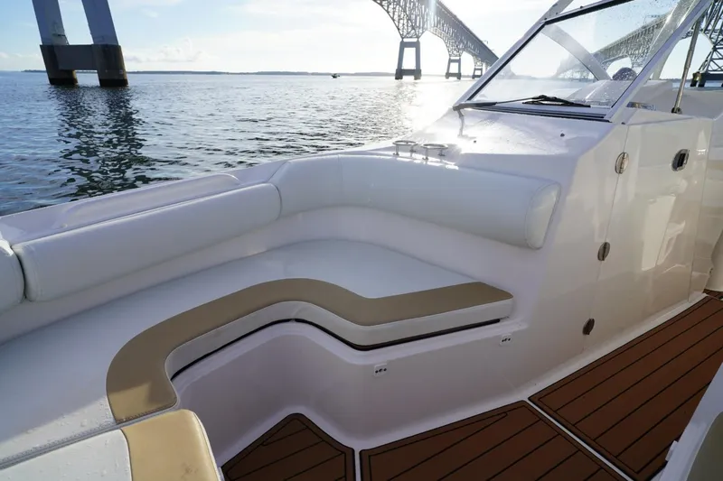  Yacht Photos Pics 2016 Edgewater 280 CX boat interior with cushioned seating, near a bridge on calm water.