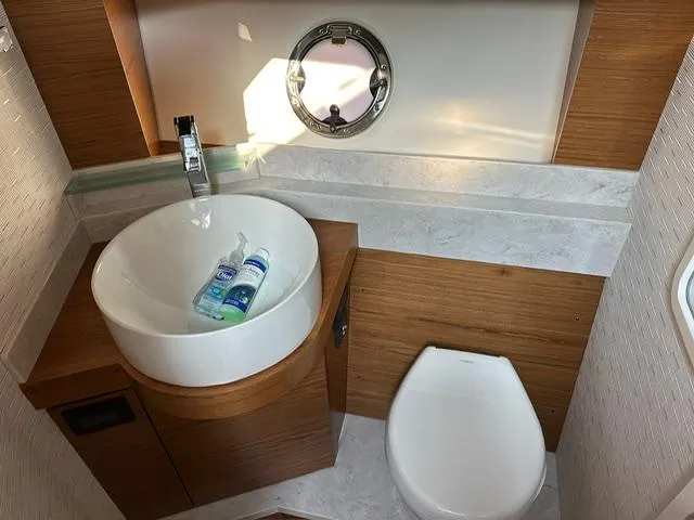  Yacht Photos Pics 2022 Tiara Yachts C39 Coupe bathroom with modern sink and toilet, featuring wood accents.