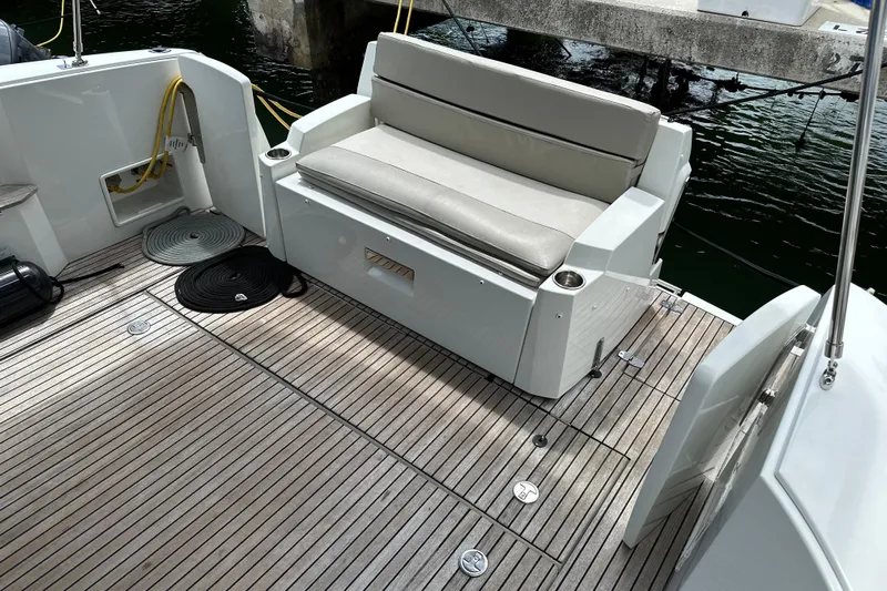 Andalucia Yacht Photos Pics 2017 Jeanneau NC 11 boat deck with cushioned seating and wooden flooring.