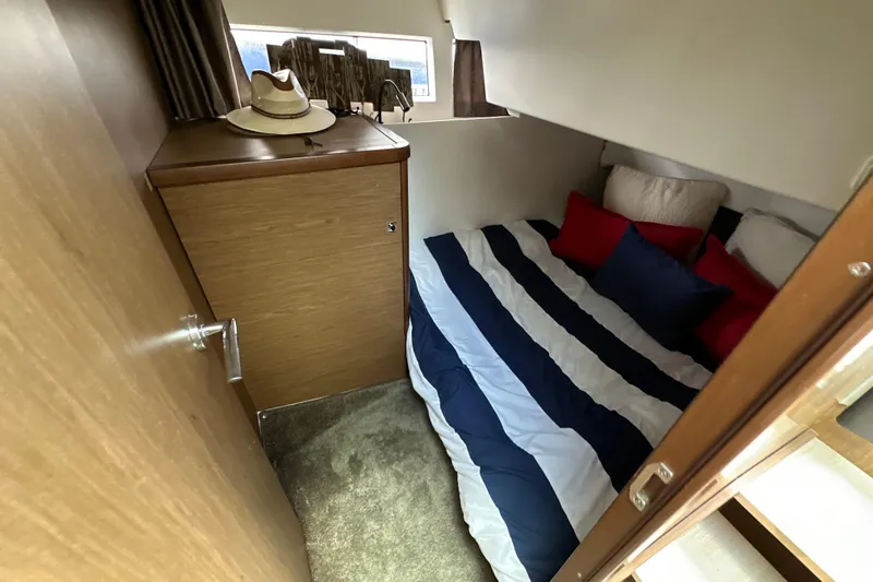 Andalucia Yacht Photos Pics Cozy cabin interior of 2017 Jeanneau NC 11 with striped bedding and wooden cabinetry.