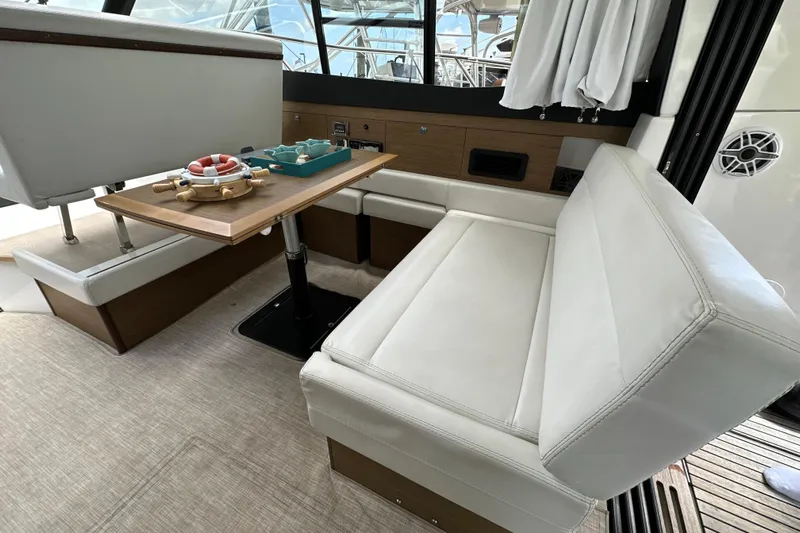 Andalucia Yacht Photos Pics Interior of 2017 Jeanneau NC 11 yacht with white seating and wooden table.