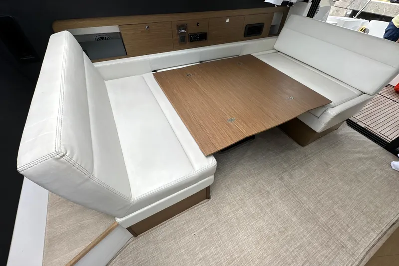 Andalucia Yacht Photos Pics 2017 Jeanneau NC 11 interior with white seating and wooden table.