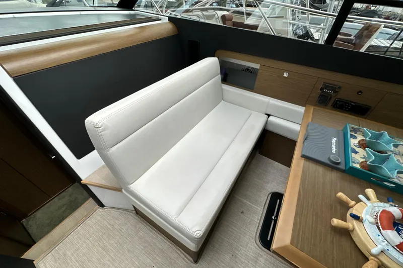 Andalucia Yacht Photos Pics Interior of 2017 Jeanneau NC 11 boat with white seating and wooden accents.