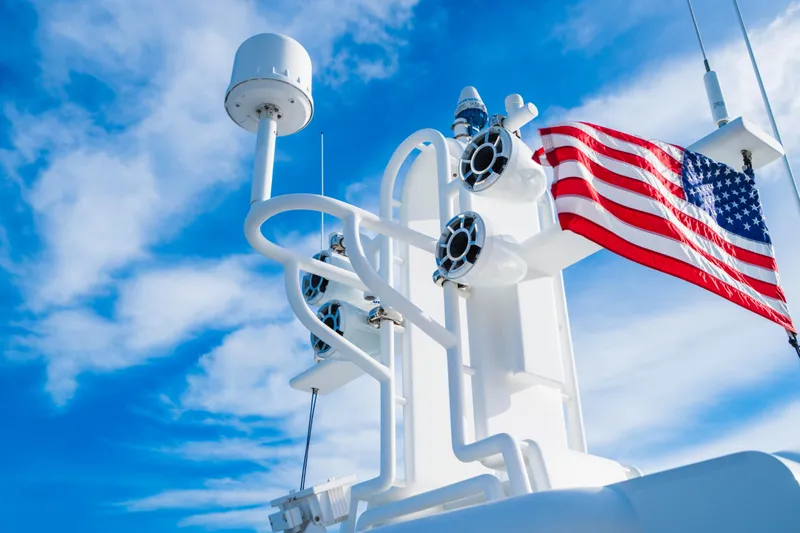 High Occupancy Yacht Photos Pics American flag on Oceanfast Custom yacht, 1989, against blue sky.