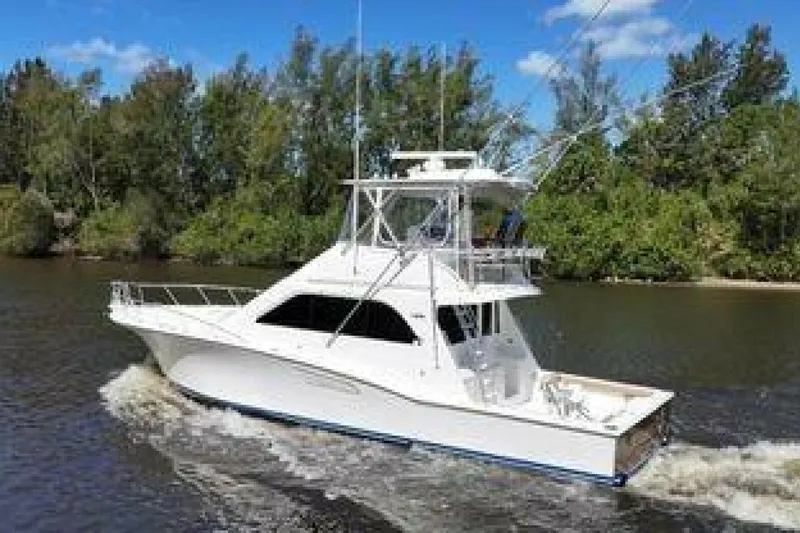 Merry Yacht Yacht Photos Pics 2004 Cabo 48 Flybridge yacht cruising on a river with lush green trees.