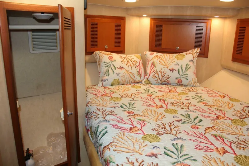 Merry Yacht Yacht Photos Pics Cozy cabin interior of 2004 Cabo 48 Flybridge with colorful coral-themed bedding.